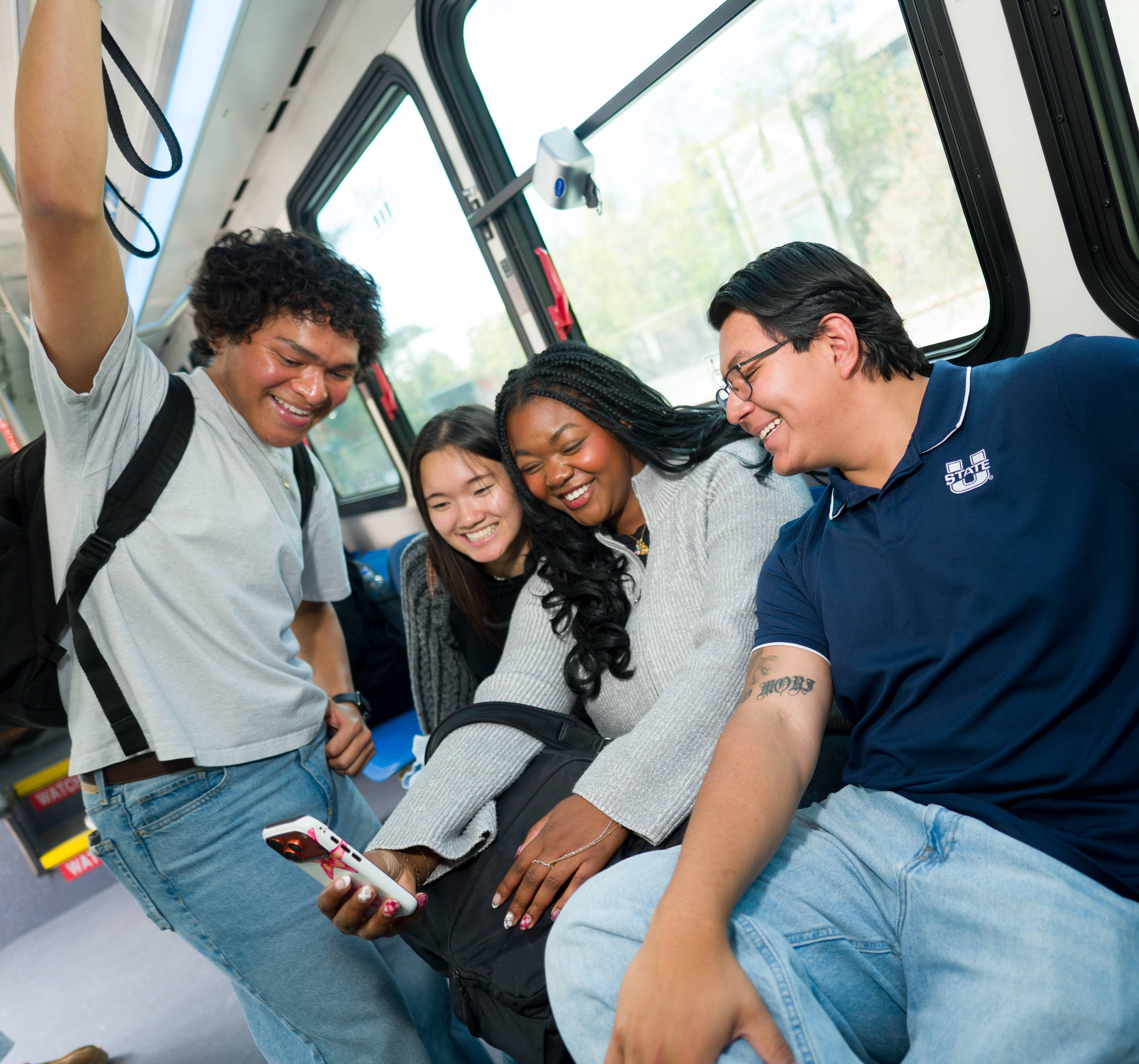four students interacting on a bus